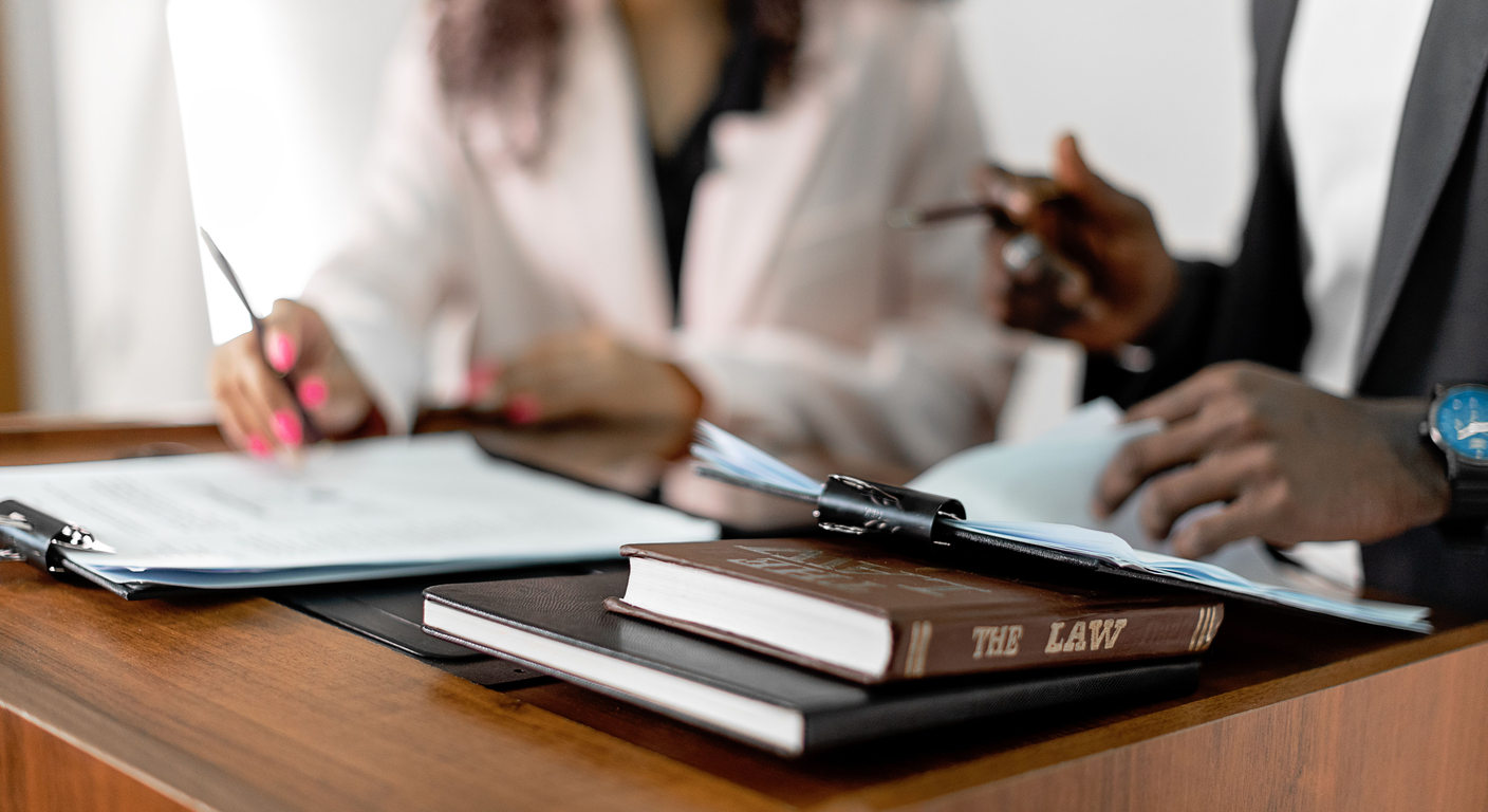 Hands reviewing documents beside law books.