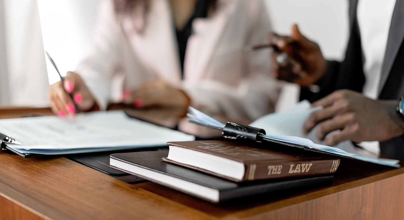 Hands reviewing documents beside law books.