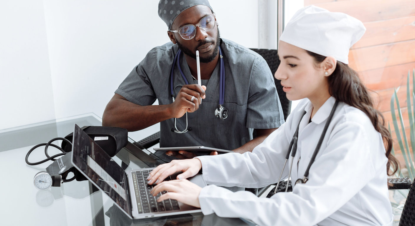Two healthcare professionals reviewing information with a laptop and tablet.